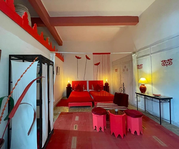 Marokkaanse slaapkamer met twee bedden en rode decoratie.