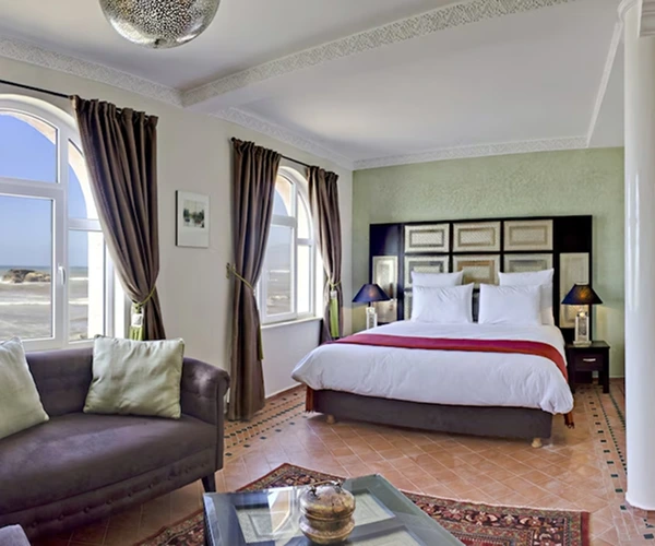 Hotelkamer met grote gebogen ramen met uitzicht op de zee.