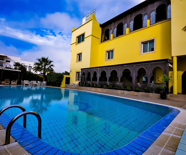 Helderblauw zwembad naast een traditioneel Marokkaans hotel.